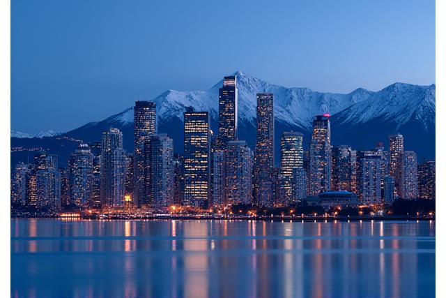 Modern Vancouver skyline at dusk with mountains in the background